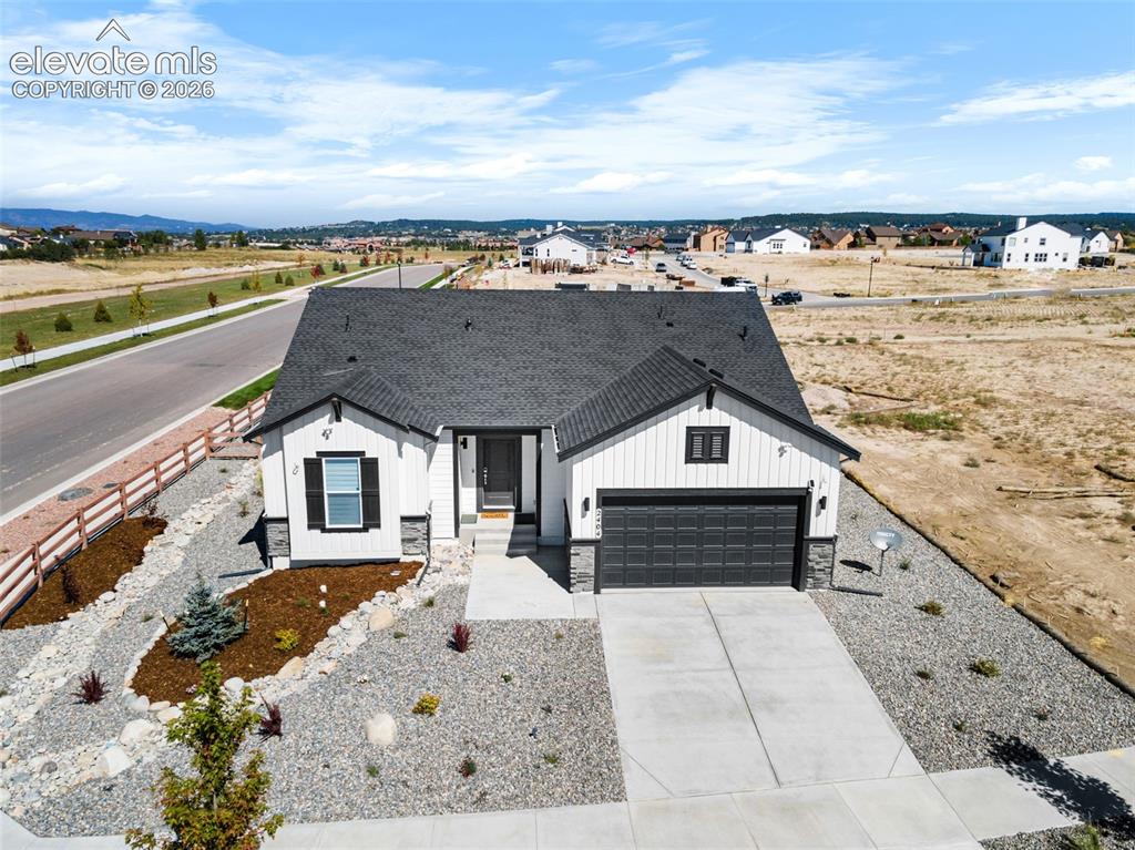 Image 8 of 38: Modern farmhouse exterior with white vertical siding and dark gray trim acc