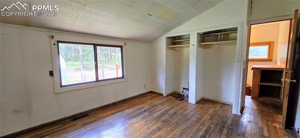 Image 17 of 48: Unfurnished bedroom featuring hardwood / wood-style floors, lofted ceiling,