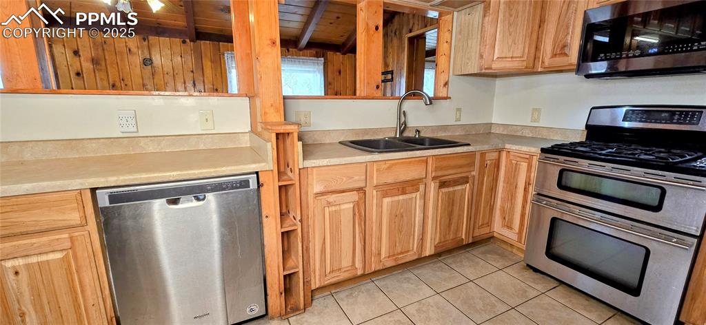 Image 21 of 48: Kitchen with appliances with stainless steel finishes, light countertops, l