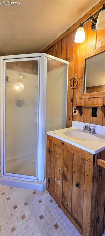 Image 25 of 48: Bathroom with wood walls, a stall shower, vanity, and tile patterned floors