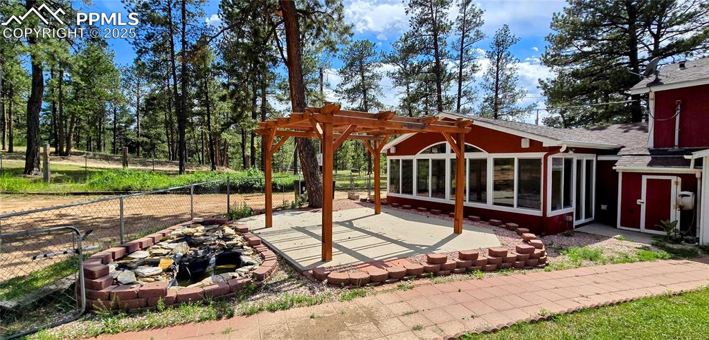 Image 28 of 48: View of patio / terrace with a pergola, a sunroom, and a fire pit