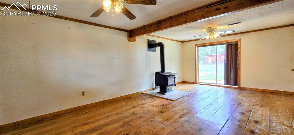 Image 32 of 48: Spare room featuring a ceiling fan, beamed ceiling, hardwood / wood-style f