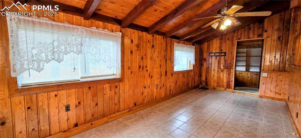 Image 33 of 48: Tiled empty room featuring wooden walls, wood ceiling, and a ceiling fan