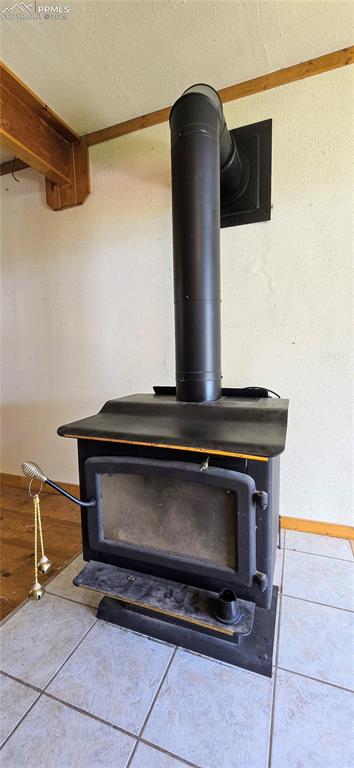 Image 34 of 48: Detailed view of a wood stove, a textured ceiling, and ornamental molding