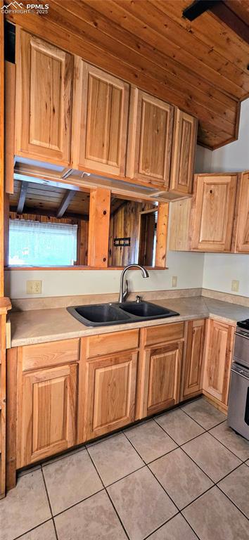 Image 38 of 48: Kitchen with light tile patterned floors, range, and light countertops