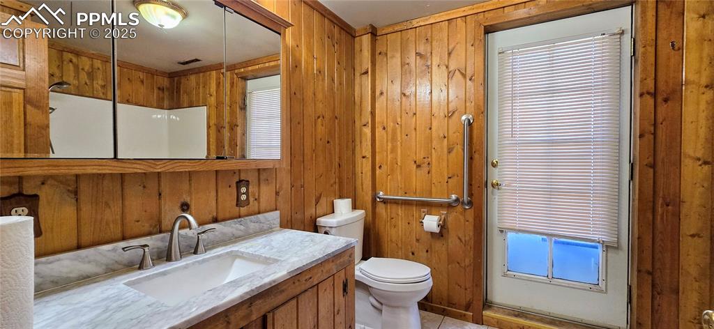 Image 5 of 48: Bathroom with wooden walls, healthy amount of natural light, vanity, and ti