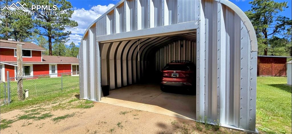 Image 6 of 48: View of parking / parking lot with driveway and a garage