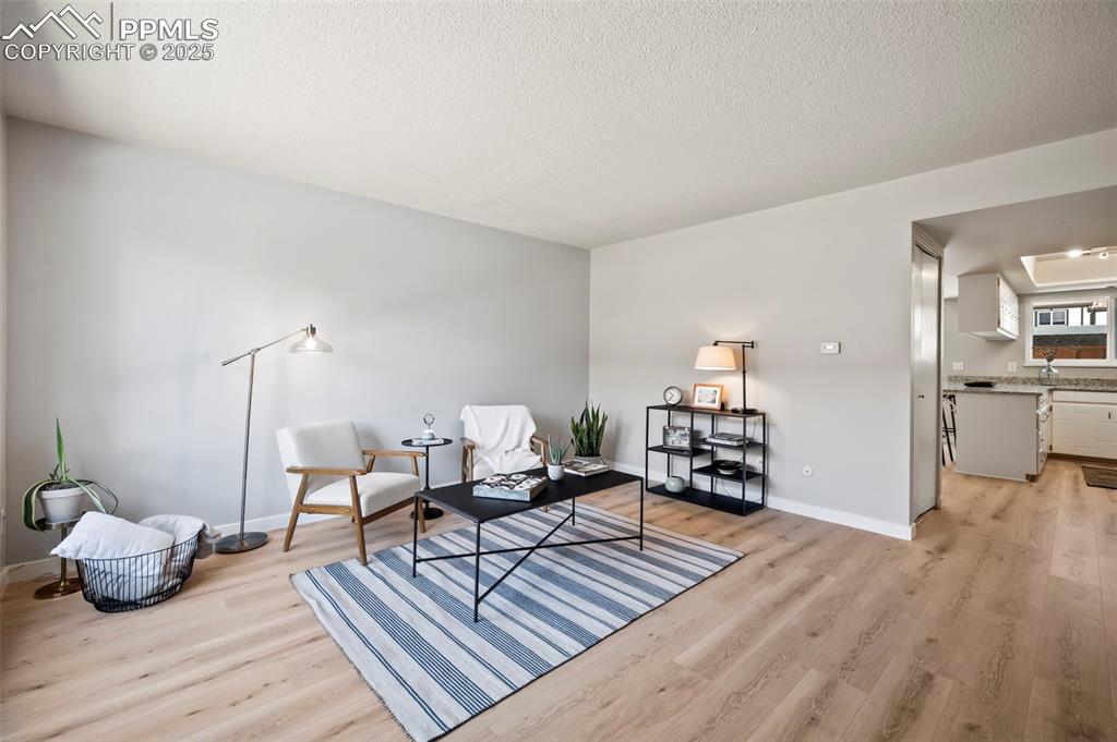 Image 2 of 22: Sitting room with light wood-type flooring and a textured ceiling