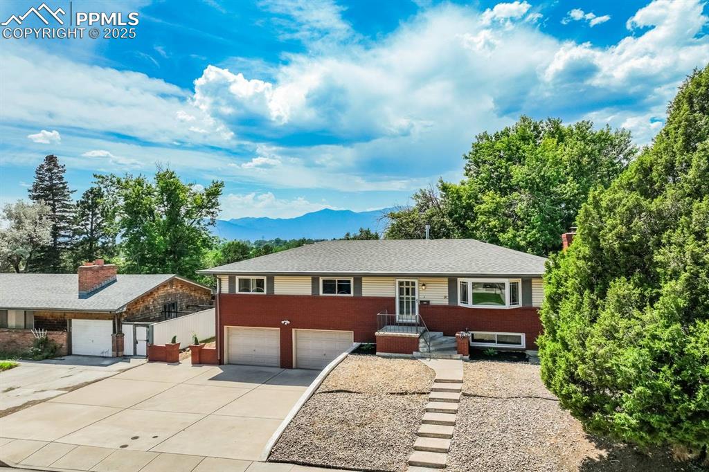 Image 26 of 37: Ranch-style home featuring driveway, a mountain view, a garage, and brick s