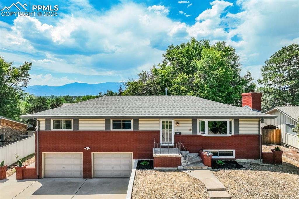 Image 31 of 37: Single story home with concrete driveway, a mountain view, brick siding, an