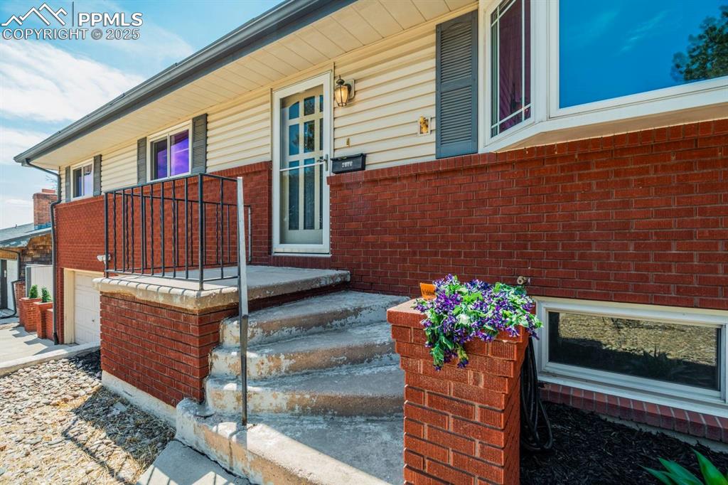 Image 4 of 37: Doorway to property featuring brick siding and a garage