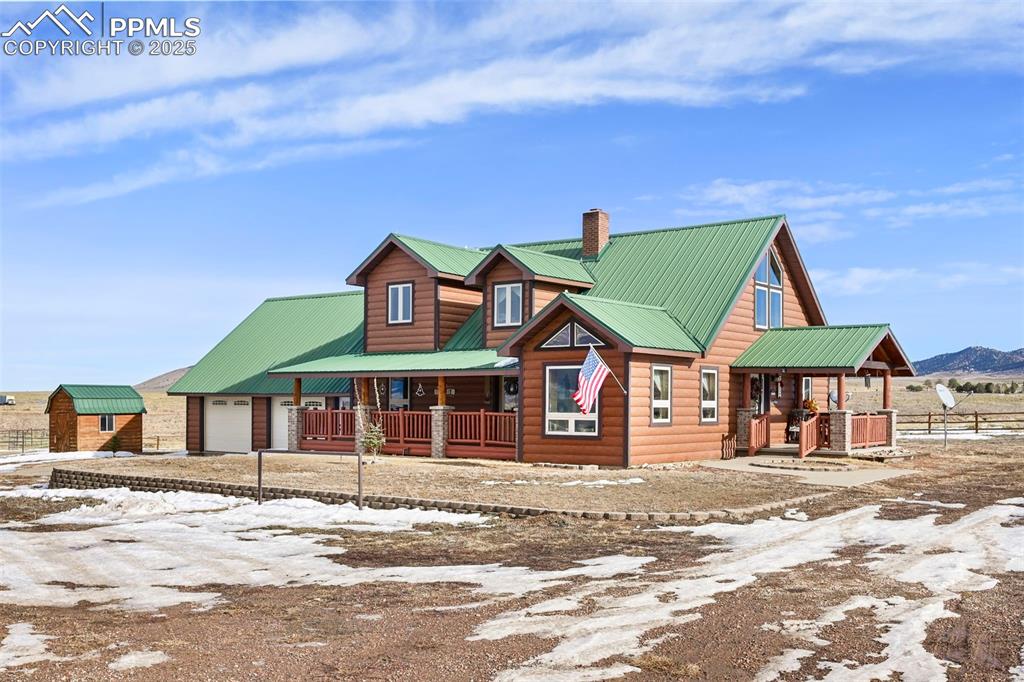 Image 12 of 50: Rustic home featuring metal roof, faux log siding, a chimney, driveway, and