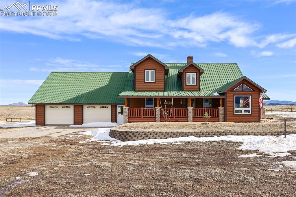 Image 13 of 50: View of front of home featuring log veneer siding, metal roof, driveway, a