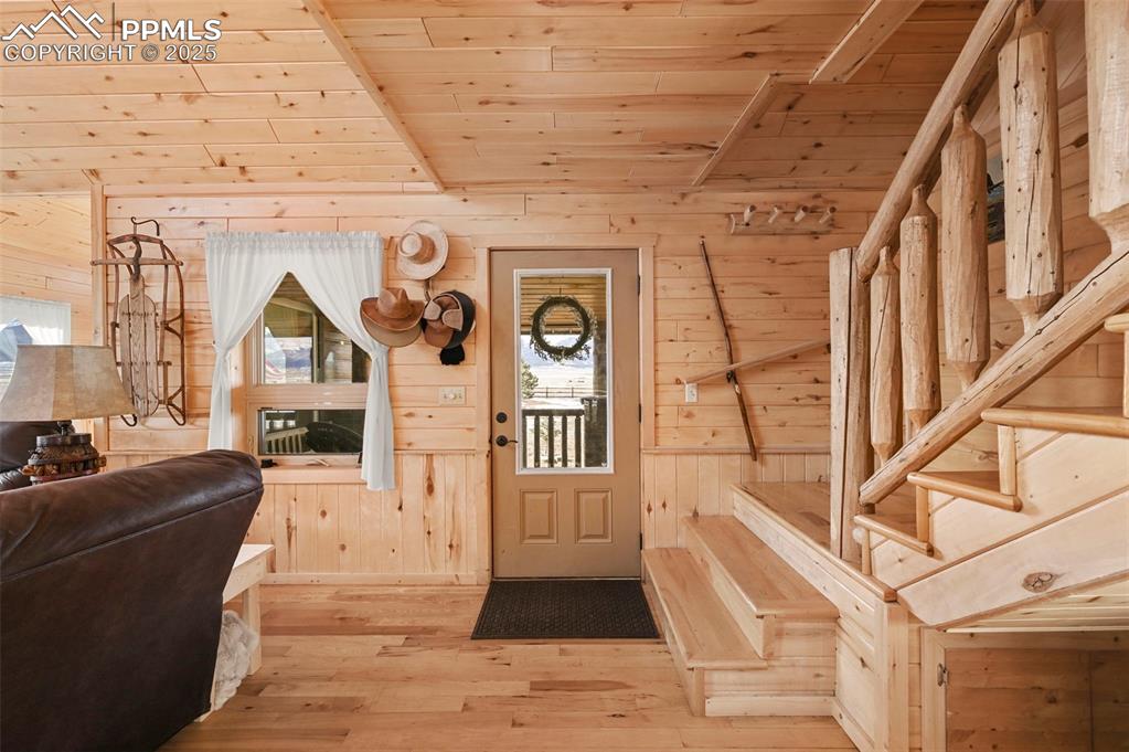 Image 18 of 50: Entryway featuring wood ceiling, wood walls, light wood finished floors, an