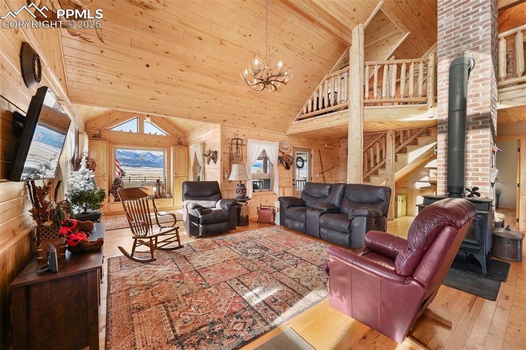 Image 20 of 50: Living area with high vaulted ceiling, wood ceiling, wood walls, a wood sto