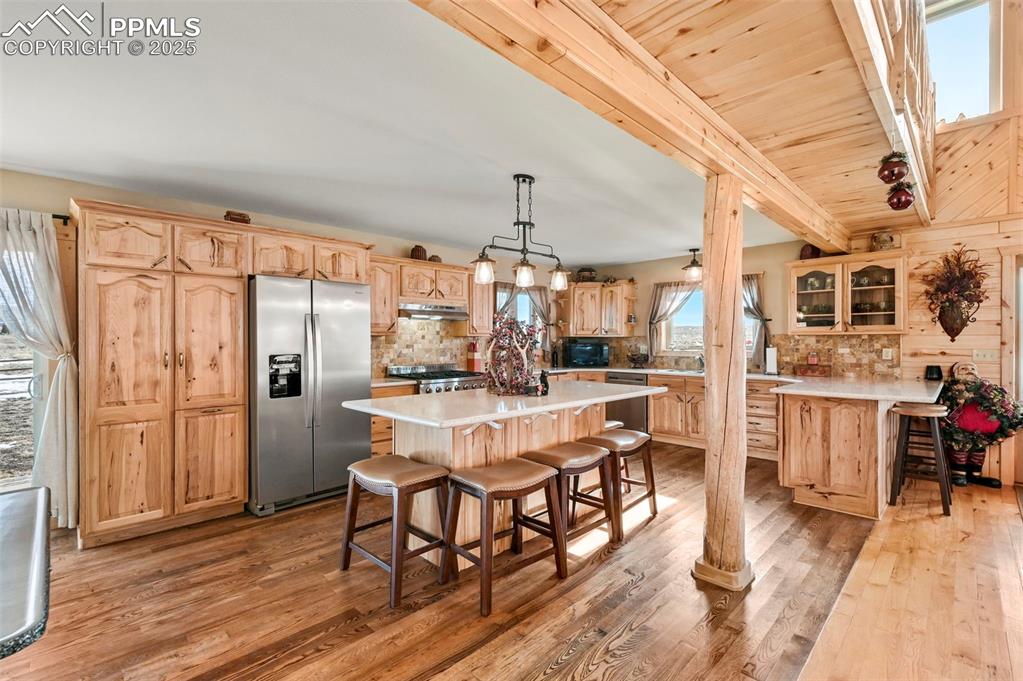 Image 24 of 50: Kitchen with a kitchen bar, stainless steel appliances, tasteful backsplash