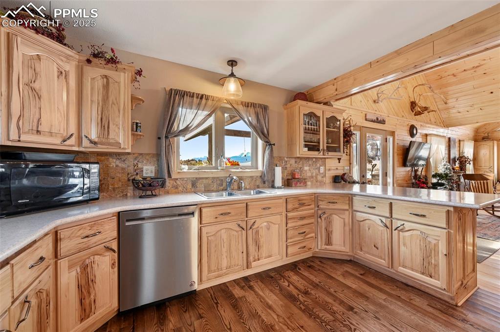 Image 25 of 50: Kitchen with stainless steel dishwasher, a sink, a peninsula, light brown c