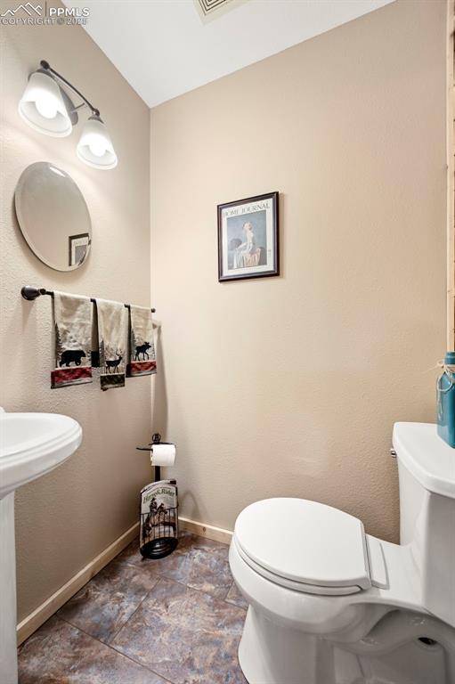 Image 31 of 50: Half bathroom with baseboards, toilet, and a sink