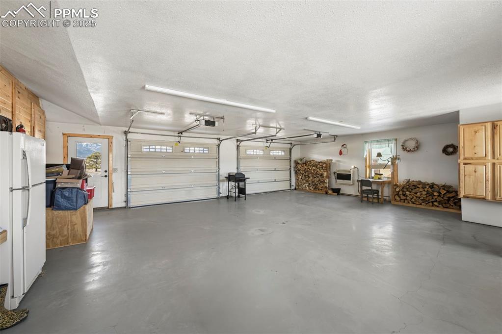 Image 32 of 50: Garage featuring a garage door opener and freestanding refrigerator