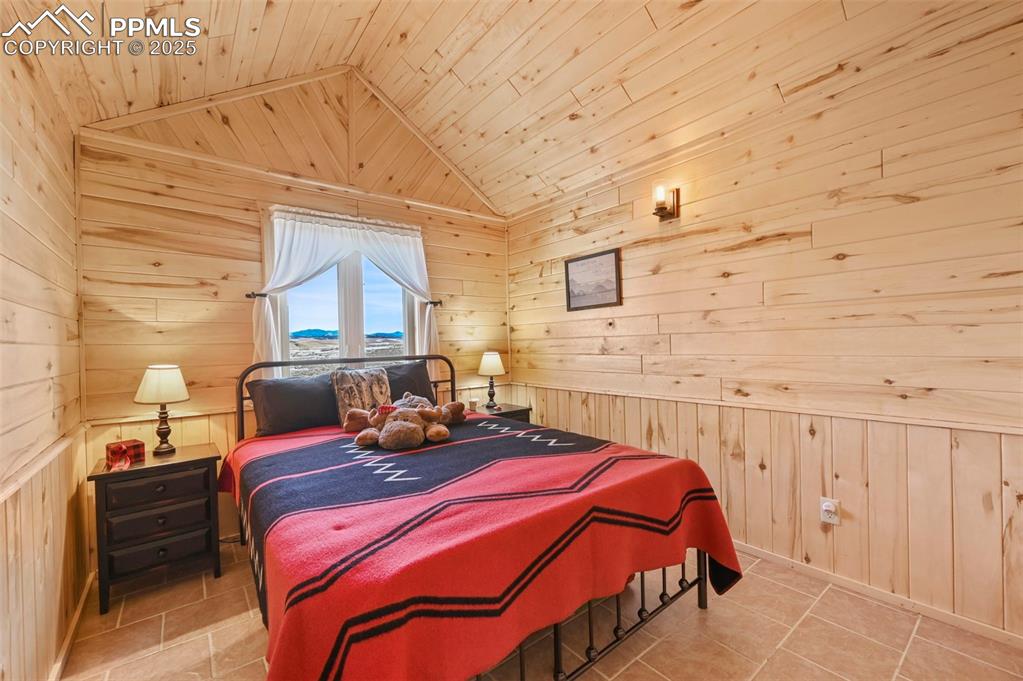 Image 35 of 50: Bedroom with wood ceiling, wood walls, and vaulted ceiling