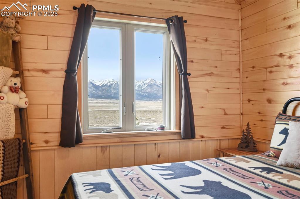 Image 38 of 50: Bedroom with wood walls and a mountain view