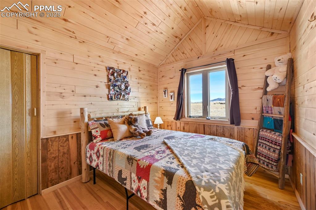 Image 39 of 50: Bedroom with wooden ceiling, wood walls, vaulted ceiling, and wood finished