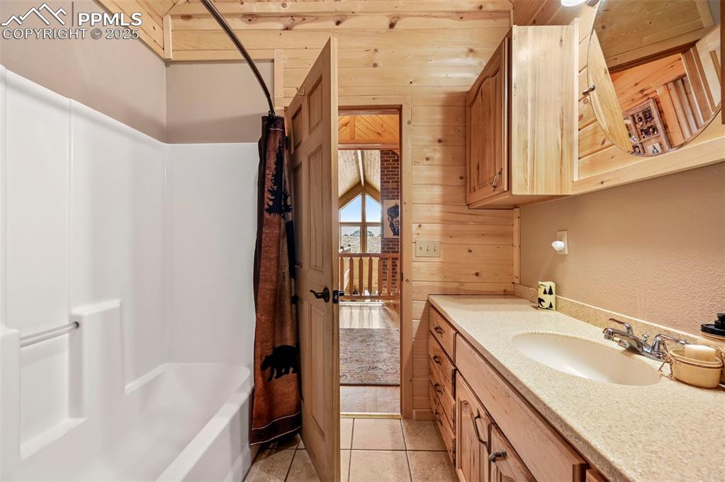 Image 41 of 50: Bathroom with shower / bath combination with curtain, tile patterned floors