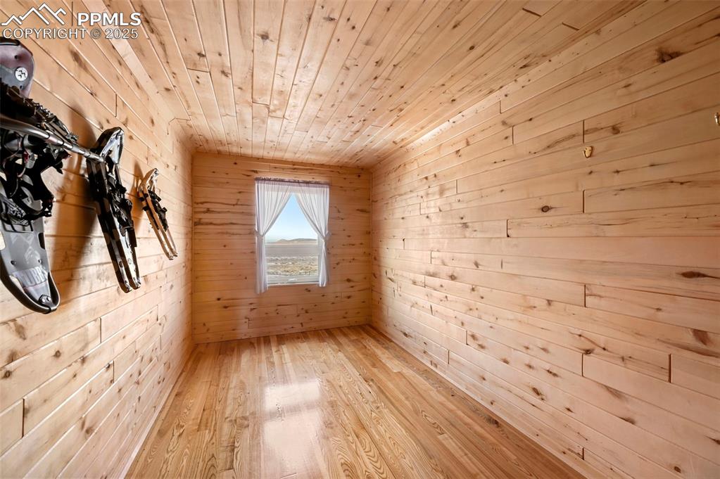 Image 42 of 50: Spare room featuring light wood-style flooring, wooden walls, and wood ceil