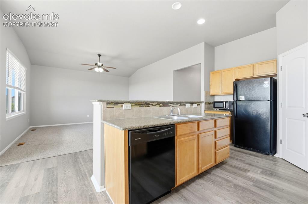 Image 12 of 31: Kitchen with wood-finish flooring, light wood cabinetry, and black applianc