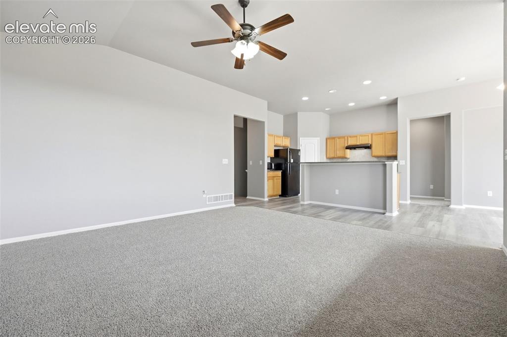 Image 13 of 31: Vaulted ceiling with a ceiling fan, light wood cabinetry, black appliances,