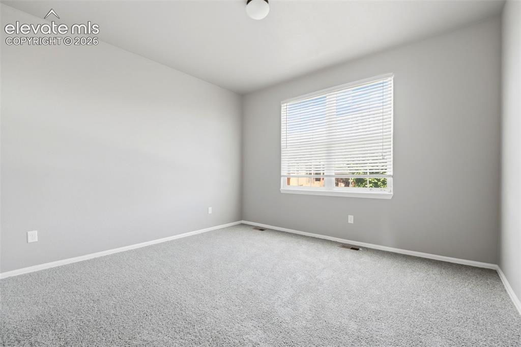 Image 14 of 31: Neutral-toned walls with light grey carpeting, white window blinds, and ove
