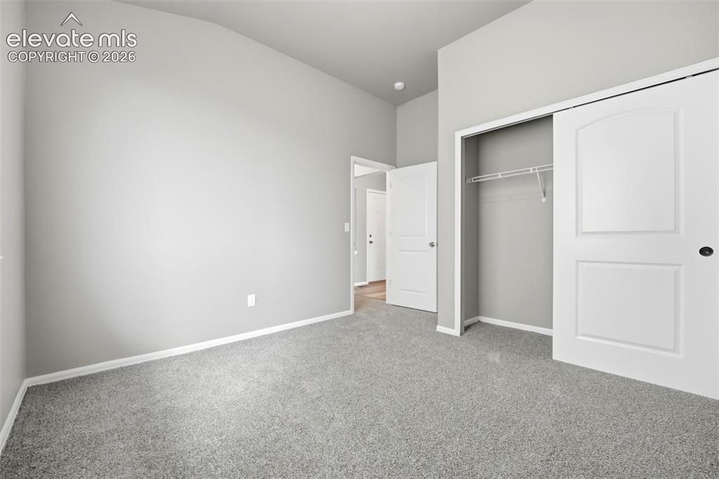 Image 16 of 31: Vaulted ceiling, neutral gray wall tones, gray carpeting, white trim, and a