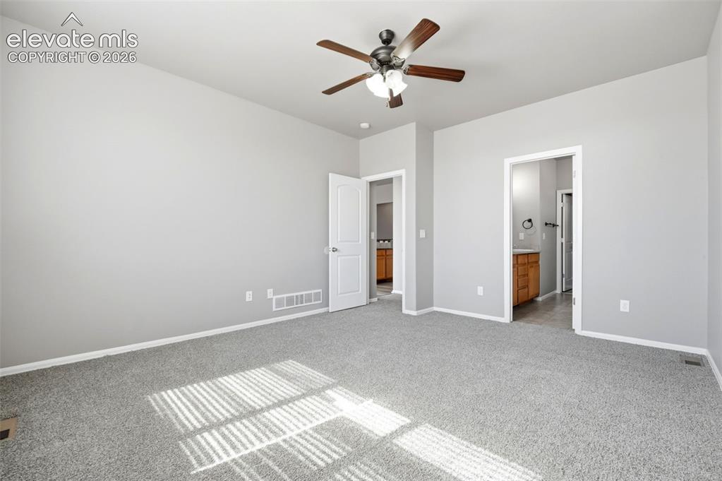 Image 17 of 31: Ceiling fan with wooden blades, light gray wall paint, and gray carpeting