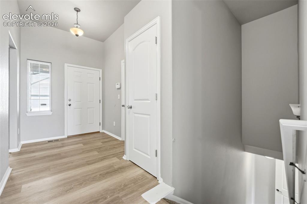 Image 2 of 31: Vaulted entry featuring wood-finish flooring, white paneled doors, and a de