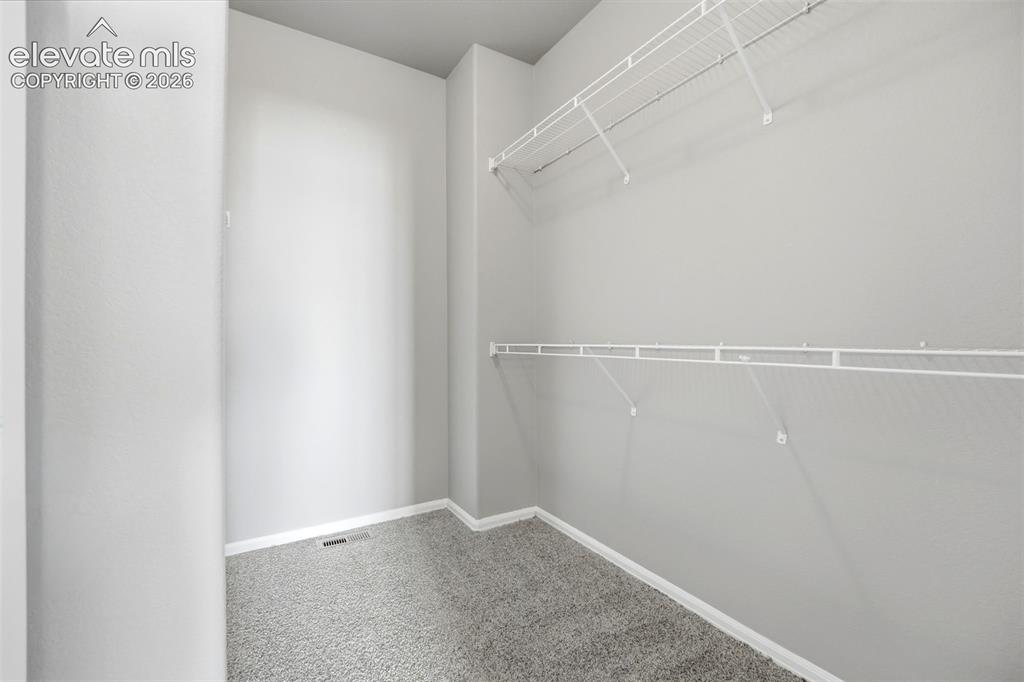 Image 21 of 31: White wire shelving, light gray wall paint, and gray carpeting