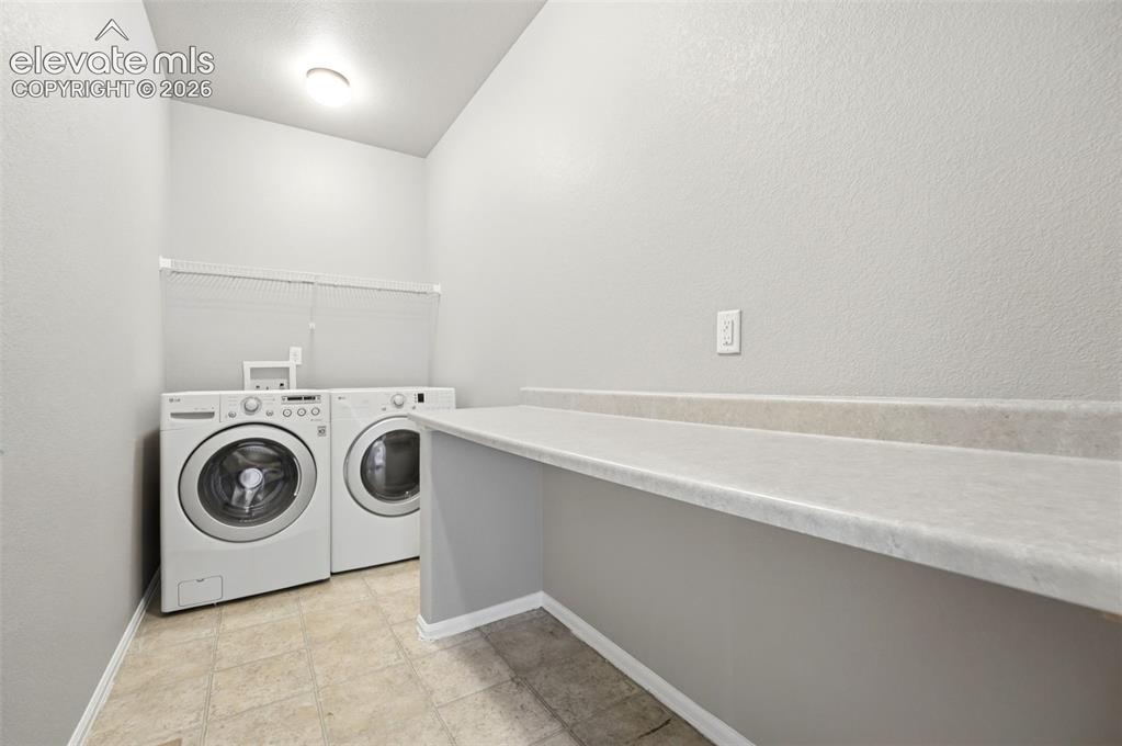 Image 22 of 31: Dedicated laundry area featuring a built-in counter, wire shelving, and neu