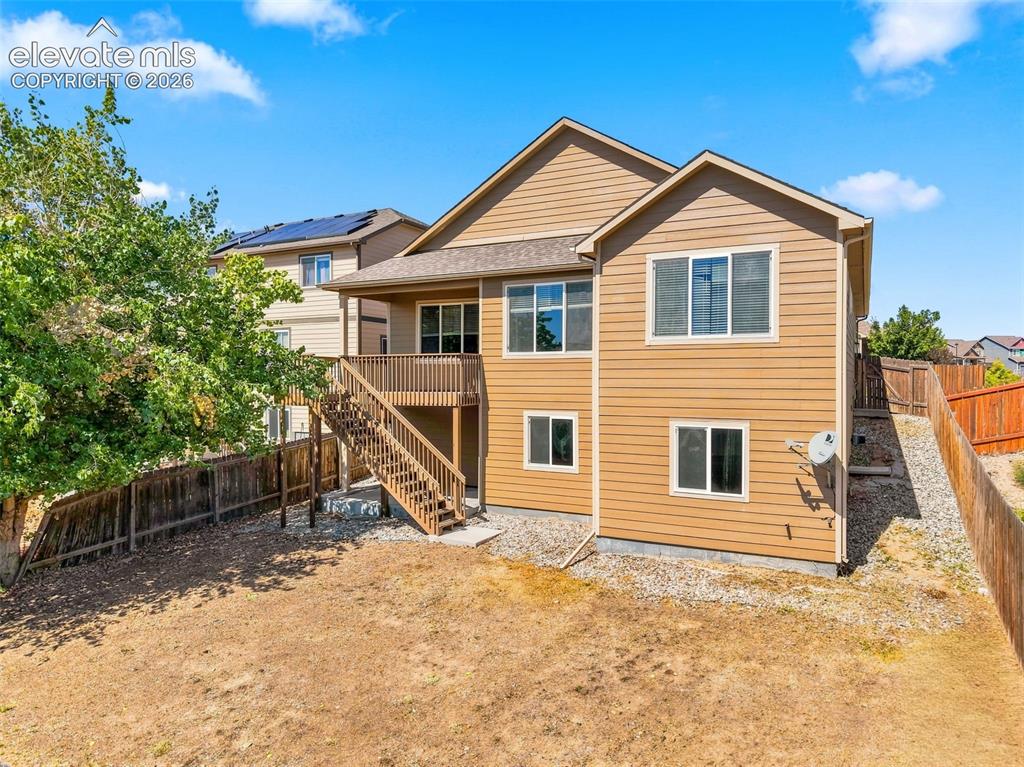 Image 28 of 31: Multi-story exterior with light brown siding, a wood-finish deck with stair