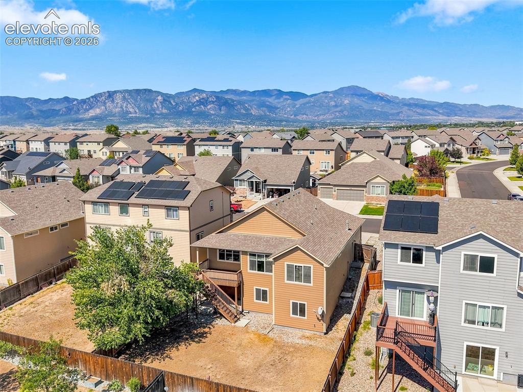 Image 30 of 31: Residential neighborhood with a mountain backdrop, featuring solar panels o