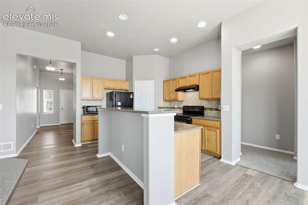 Image 6 of 31: Kitchen with wood-finish cabinetry, built-in appliances, a tiled backsplash