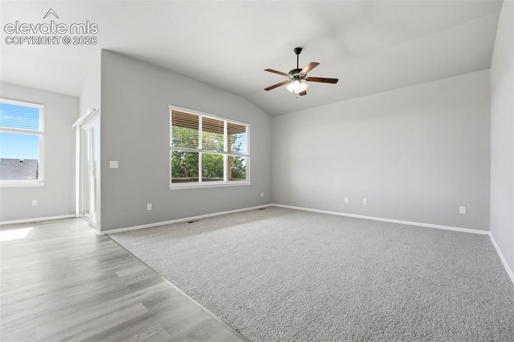 Image 8 of 31: Vaulted ceiling with a ceiling fan, light gray carpeting, wood-finish floor