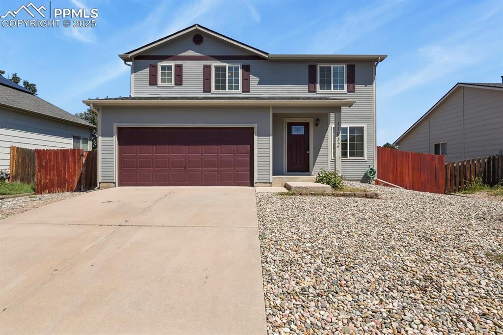 Caption: Traditional-style home featuring a garage, driveway, and a porch
