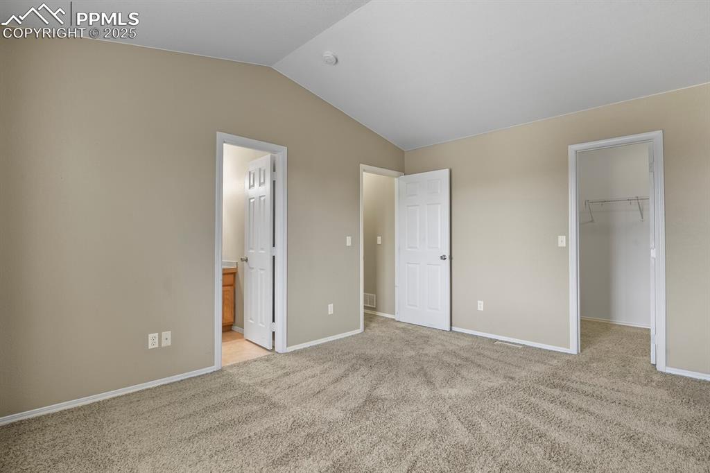 Image 22 of 35: Unfurnished bedroom featuring a walk in closet, lofted ceiling, light color