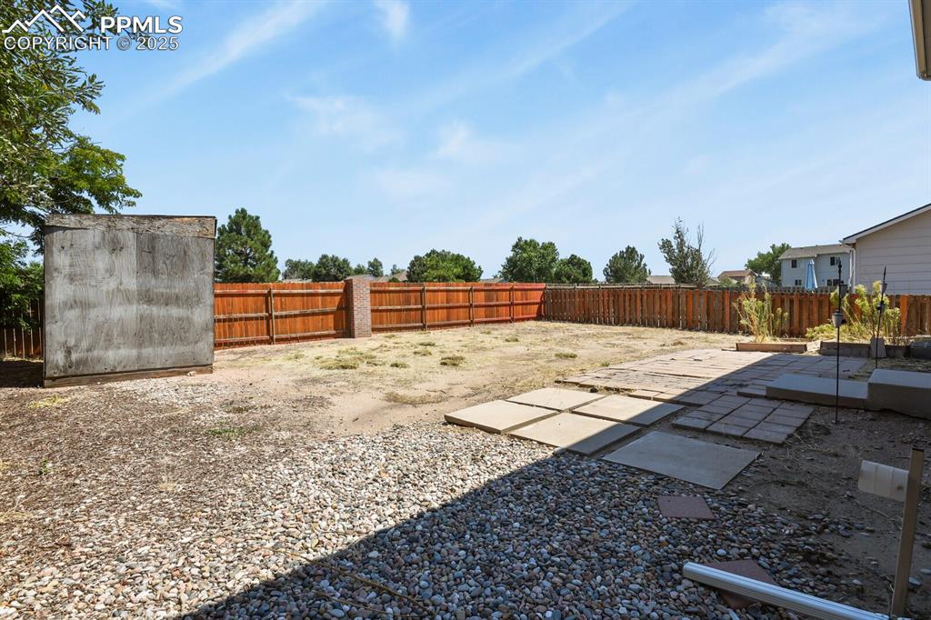 Image 33 of 35: Fenced backyard with a patio