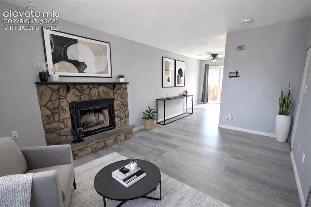 Image 10 of 24: Living area featuring a stone fireplace with a dark mantel, wood-finish flo