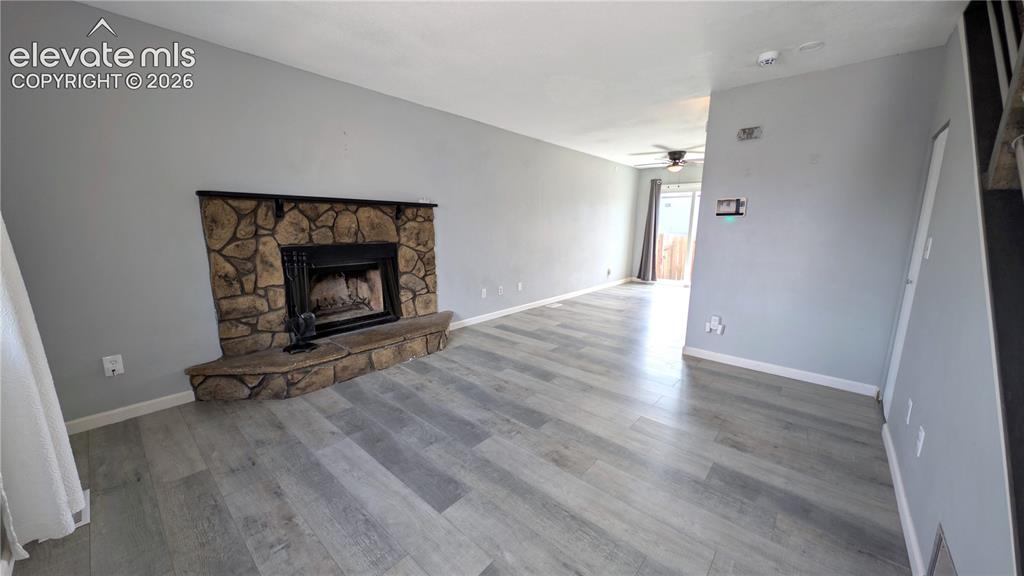 Image 11 of 24: Open living area featuring wood-finish flooring, a stone-clad fireplace wit