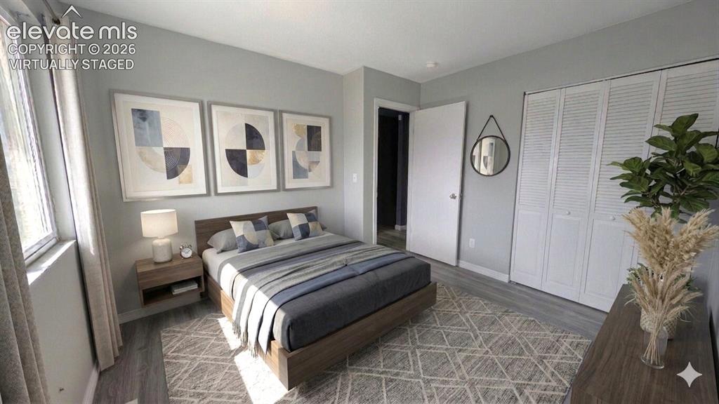 Image 14 of 24: Bedroom featuring light grey walls, wood-finish flooring, a window with ver