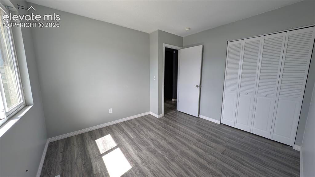 Image 15 of 24: Room featuring wood-finish flooring, light gray wall paint, and white baseb