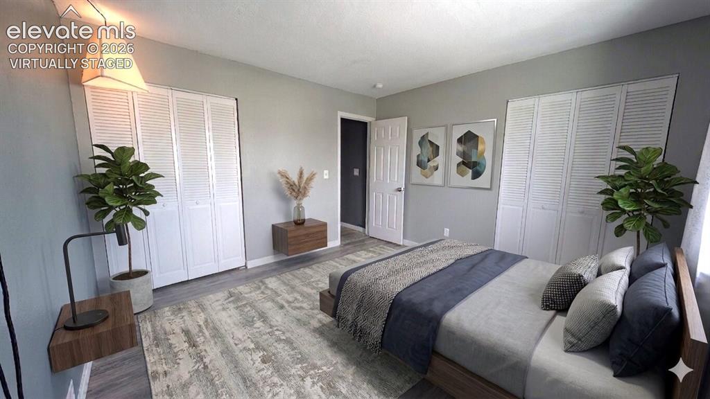 Image 16 of 24: Bedroom featuring light gray walls, wood-finish flooring, white louvered cl