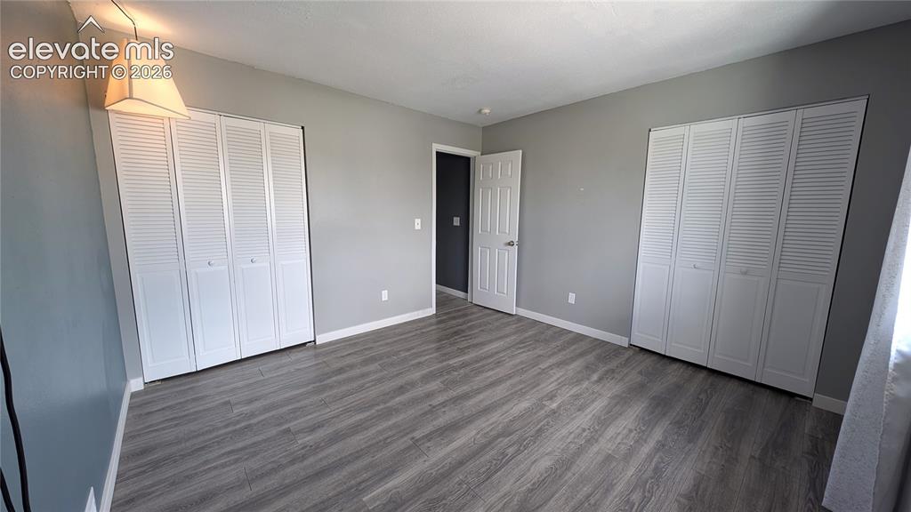 Image 17 of 24: Spacious room featuring wood-finish flooring, two sets of bi-fold louvered