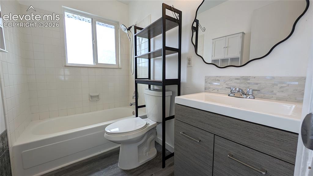 Image 19 of 24: Bathroom featuring a white bathtub, white tiled shower surround, and a vani